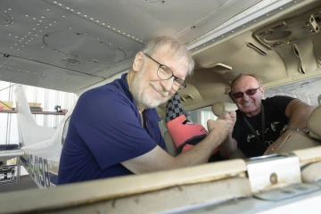 Two men fist bump on a small airplane