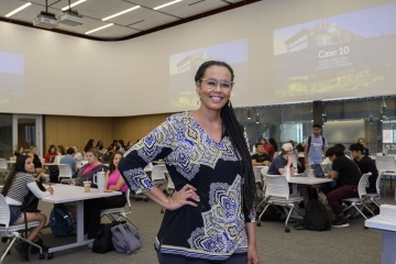 Woman stands in front of a university classroom.