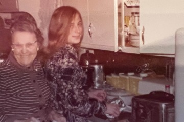 old photo of a grandmother and her granddaughter in a kitchen