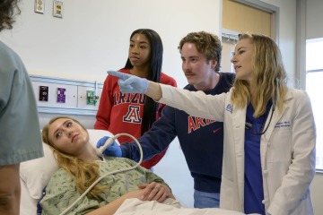 A faculty member instructs students administering an ultrasound to a patient’s neck 