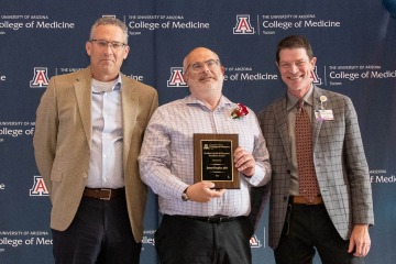 Dr. Clemens (left) and Dr. Moynahan (right) present the Graduate Medical Education Excellence Award to Dr. James Knepler.
