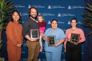 Four smiling UArizona College of Medicine – Tucson faculty members, three of whom are holding plaques, pose for a photo.