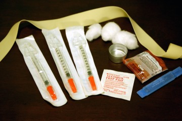 The contents of a needle exchange kit: a torniquet, cotton balls, a pot for cooking drugs, a condom, sterile water, alcohol swabs, and new needles