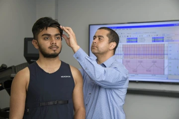 Dr. Almeida attaches sensors to a research study participant. The sensors will give researchers real-time physiological data as the participant exercises on a treadmill.