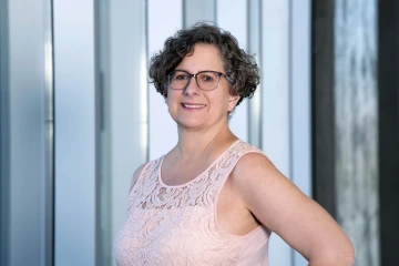 Portrait of professor Maria Kenneally wearing a ping blouse and smiling. 