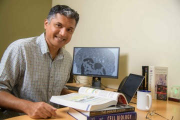 portrait of immunologist Deepta Bhattacharya at his desk at the University of Arizona Health Sciences