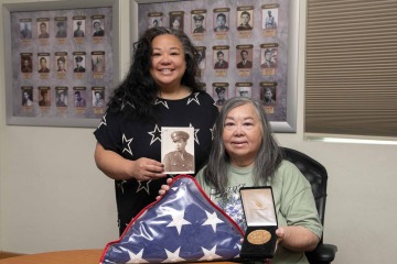 Tiffany Wong Grey holds a photo of her grandfather Chuck Gin while standing next to her mother, Katie Wong, who is holding a replica of his Congressional Gold Medal awarded to Chinese American Veterans of World War II.