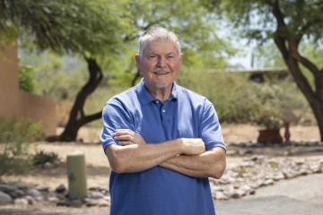 Melvin Hector, MD, stands outside wearing a blue shirt. 