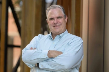 A portrait of Justin Starren, MD, PhD, standing outside.