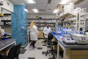 Two researchers in white coats stand in a lab.