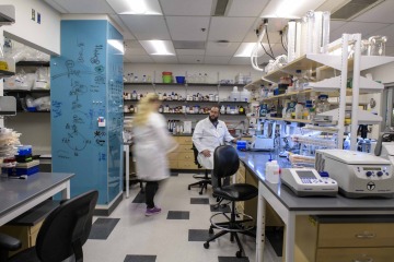 Two researchers in white coats stand in a lab.