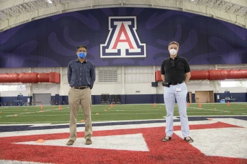 Dr. Deepta Bhattacharya and Dr. Janko Nikolich stand socially distanced on the University of Arizona indoor football practice field that was repurposed as an antibody testing station during the pandemic. 