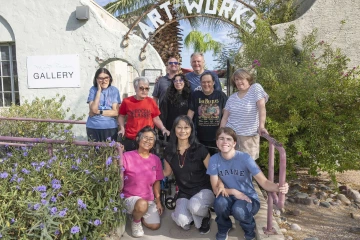 Yumi Shirai poses with a group of ArtWorks staffers and artists beneath the ArtWorks sign.