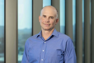 Portrait of Michael Kuhns, PhD, indoors in front of windows