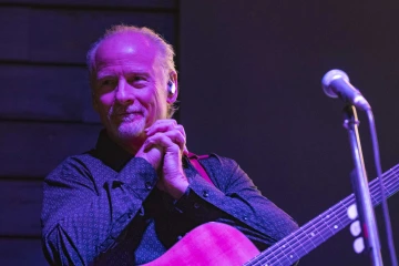 Closeup photo of John Woolf, with a guitar 