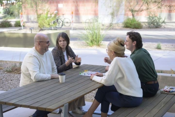 Jillian Leaver with her parents and brother playing a board game outside at a picnic table.  