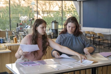 Jillian Leaver and Hunter Ackley sitting inside a café and reviewing documents