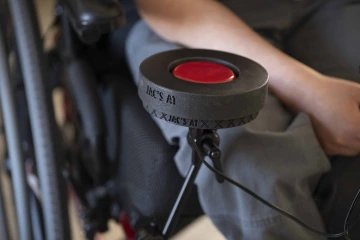 A round plastic holder with a large red button in the center