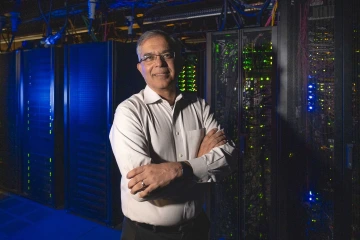 A portrait of Nirav Merchant in front of the University of Arizona’s supercomputers