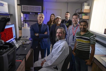 Six people stand around one person in a lab coat looking at the camera.