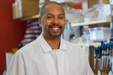 Portrait of researcher Michael Johnson wearing a lab coat in his laboratory at the University of Arizona Health Sciences