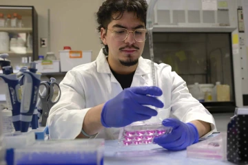 Student holds a tray and syringe in a University of Arizona Health Sciences research laboratory