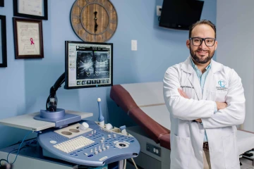 portrait of Dr. Rogelio Robles-Morales wearing a white coat inside a room at gynecologic oncology practice office