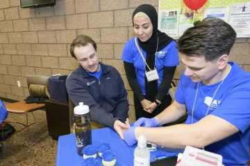 A student demonstrates how to use a glucose monitoring device