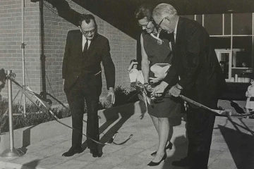 Black and white historical photo of U of A College of Nursing Dean Gladys E. Sorensen standing alongside two men in suits at a ribbon cutting ceremony for the college.