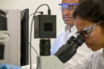 Two researchers looking through microscope
