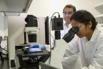 A researcher peers through a lens to analyze tumor cells