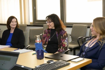 Terry Badger sits at a table with two other women in a meeting.