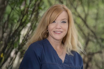 Portrait of Deborah Gorombei smiling in an outdoor setting.