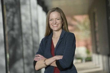 Portrait of University of Arizona Health Sciences researcher Kate Ellingson, PhD, standing with her arms crossed in an outdoor setting.