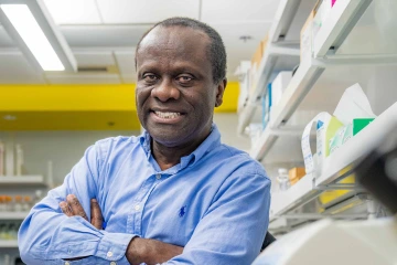 Ebenezer N. Yamoah, PhD, leans against a machine in a lab with his arms crossed in front of him.
