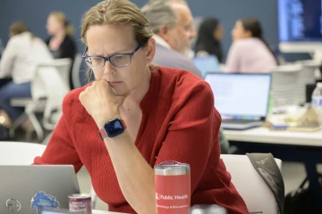 Kacey Ernst, PhD, MPH, stares at a lap top screen with a concerned look on her face.