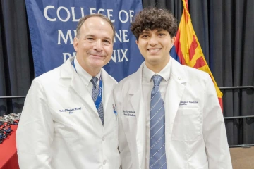 Jerry Ruvalcaba (right), a medical student, stands smiling in his white lab coat next to Dr. Fredric Wondisford, Dean of the University of Arizona College of Medicine – Phoenix, at the college's White Coat Ceremony.