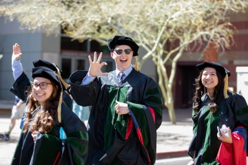Class of 2022 graduates give the bear down sign on their way to commencement in Phoenix.