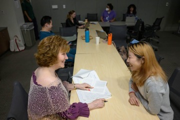 Woman sitting at a table talking to an adult student.