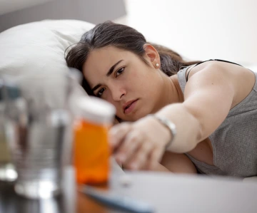 women reaching for prescription bottle