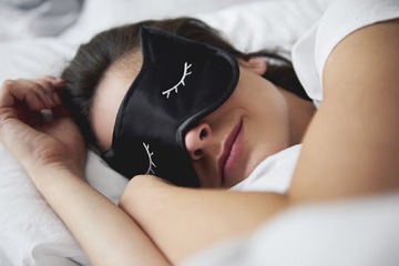 Female in bed wearing a sleep mask