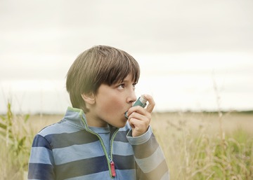 Boy using an inhaler outdoors