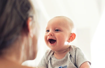 A baby smiling at it's mother