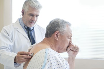 Male doctor examining patient in hospital gown