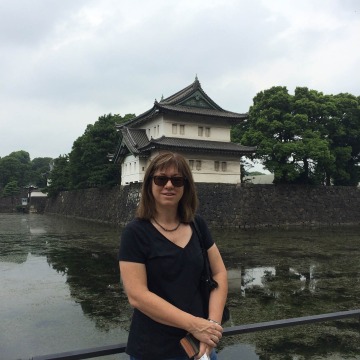 Dr. Carol Gregorio standing in front of a rive and building in Japan. 