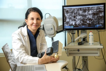 Clara Curiel Lewandrowski, MD, in front of a screen showing the images produced by the portable confocal microscope in development at the University of Arizona.