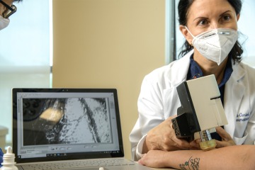 Clara Curiel-Lewandrowski, MD, takes an image of a person’s arm with the portable version of a confocal microscope. It provides a “map” of the skin for a doctor to use in diagnosing or treating skin cancer. 