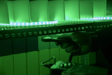 a hand holds a light meter under a strand of green led lights