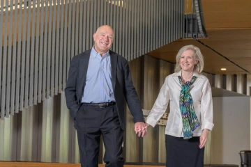 Man and woman holding hands in the Health Sciences Innovation Building Forum.