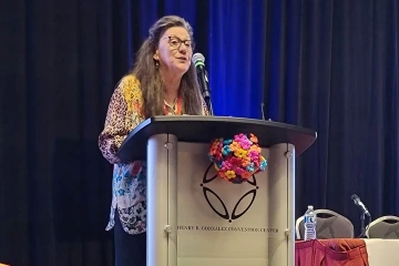 woman stands at lecturn during award presentation